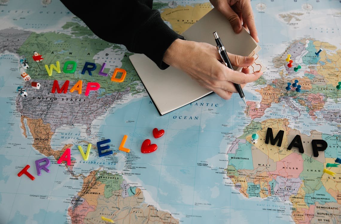 Main qui prépare un itinéraire sur une carte du monde pour comparer un vol multi-destinations