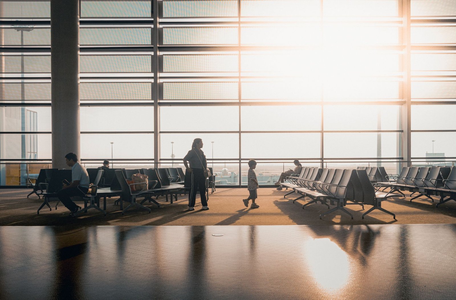 Voyageurs dans un terminal baigné de lumière au lever du jour pour illustrer la reprise du rythme local après l’arrivée