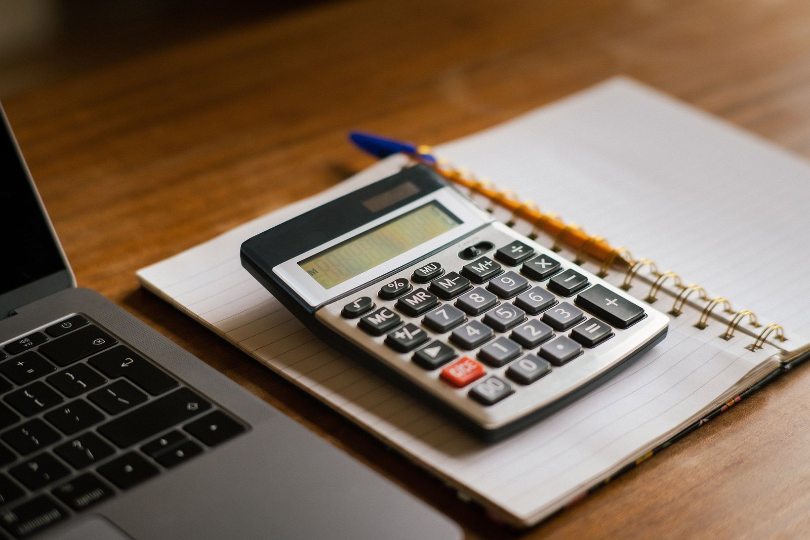 Ordinateur portable et calculatrice sur un bureau pour illustrer la préparation d’un budget voyage réaliste
